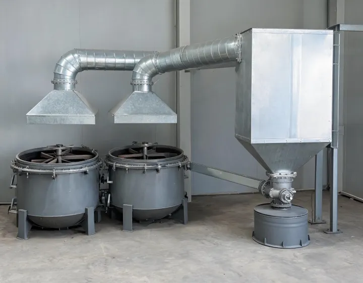 Plant floor cartridge dust collector with hoods, duct mains and hopper discharge into a sealed drum